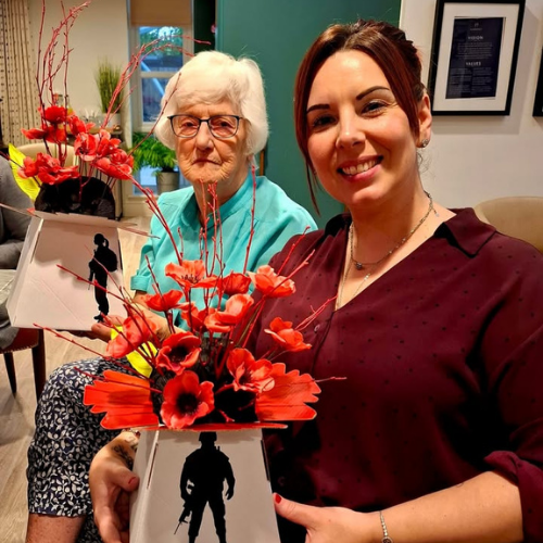 resident and staff member holding poppies